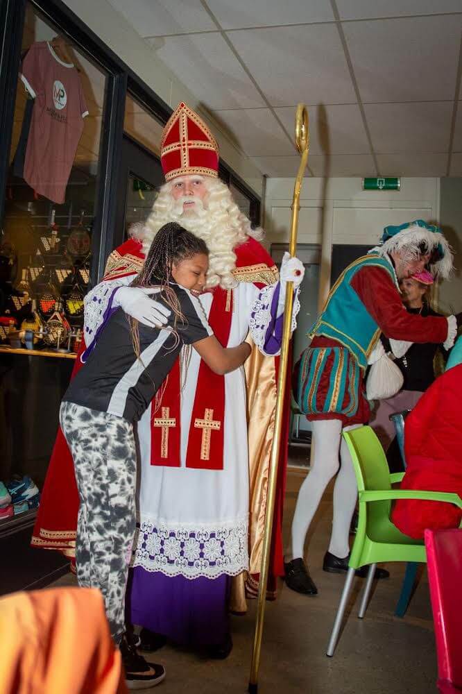 Kind ontvangt aandacht van Sinterklaas tijdens huisbezoek
